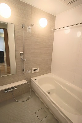 白いバスタブ、鏡とシャワー付きの浴室。
