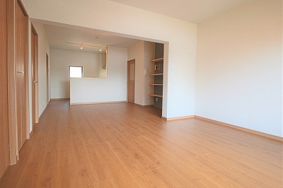 木目調の床と建具、白い壁紙のLDK、キッチンには小窓付き。