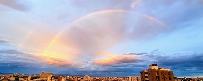 建ち並ぶマンションの上空に虹がかかっている写真